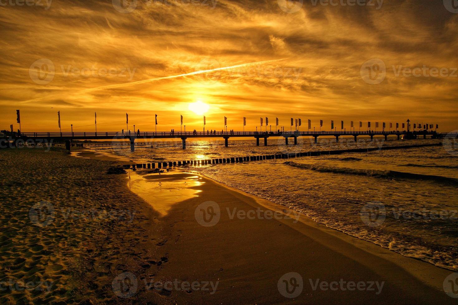 The pier in Zingst at sunset bathed in orange light photo