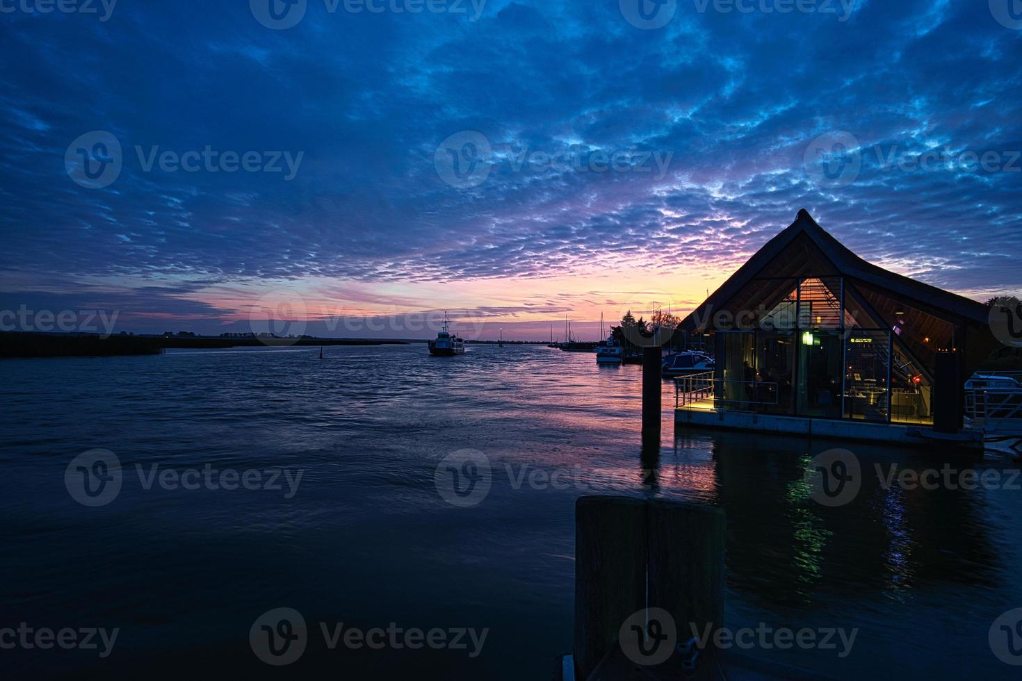 from the harbor in zingst the bodden view with burning sky with house. photo