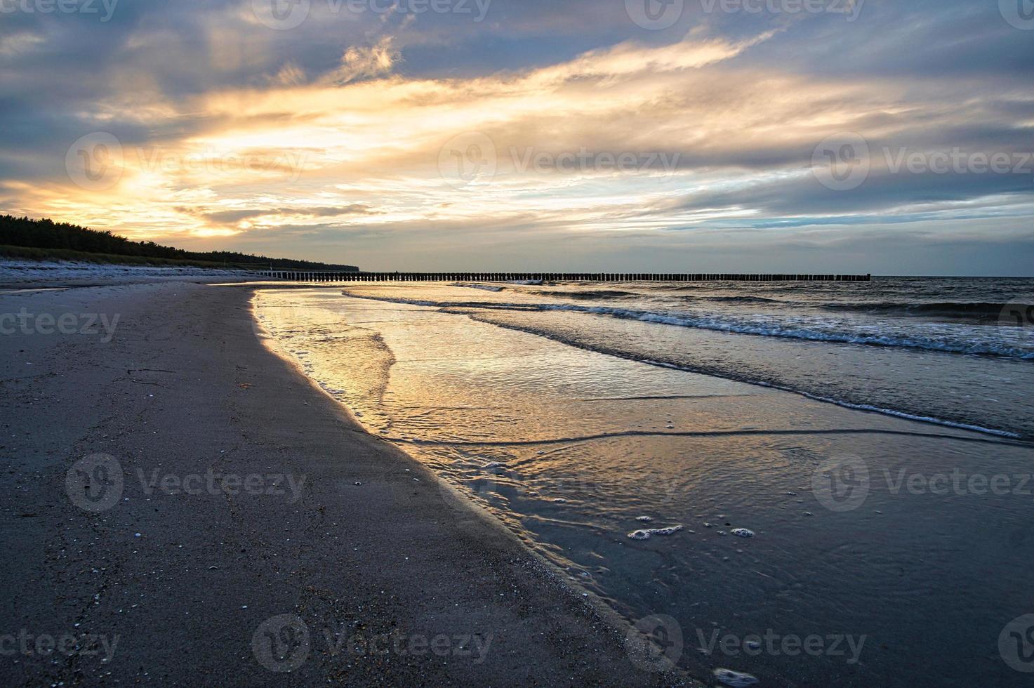 puesta de sol en la costa báltica con nubes en el cielo y reflejos en el agua. foto