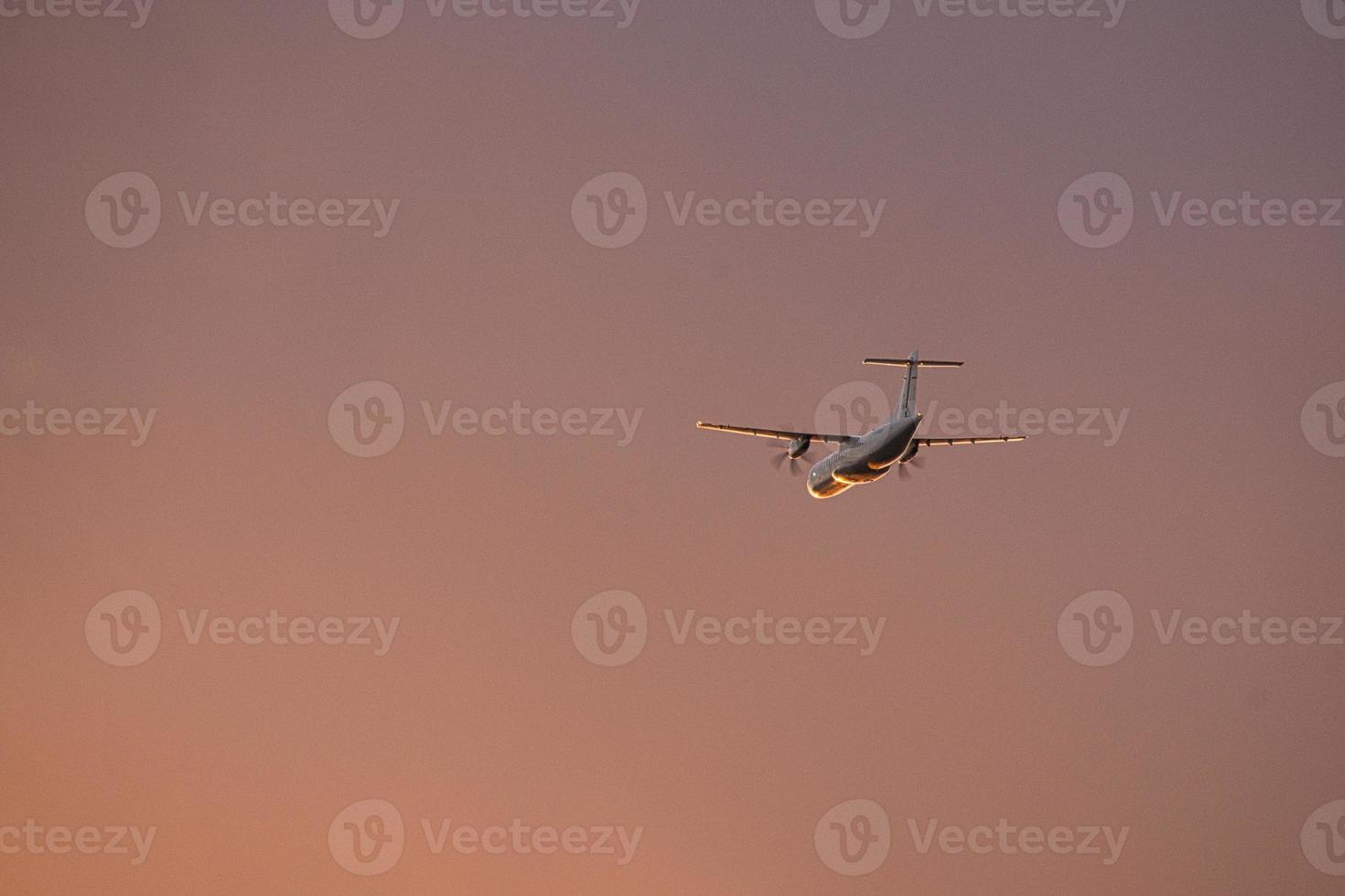 airplane in the evening sky in luminous horizon. photo