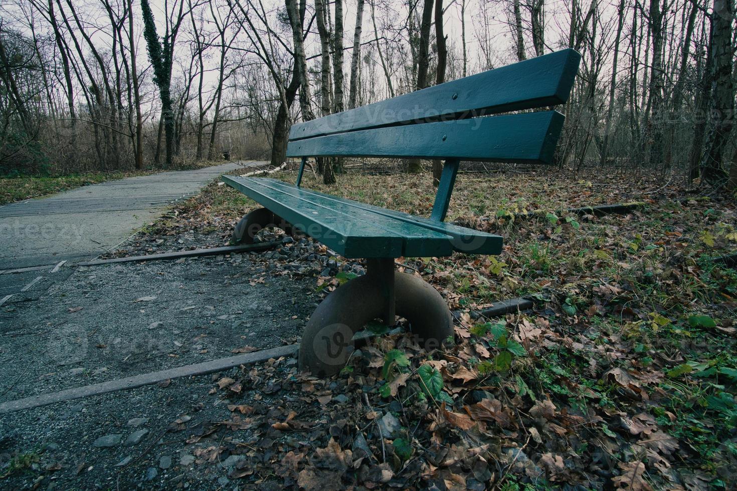 banco de parque de madera sobre vías de tren abandonadas en un parque en otoño. disfrutar solo foto