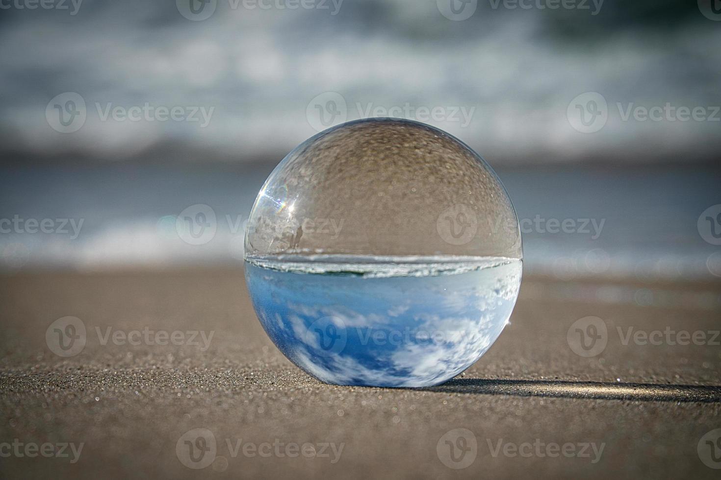 Glass globe on the beach of the Baltic Sea in Zingst in which the landscape is depicted. photo