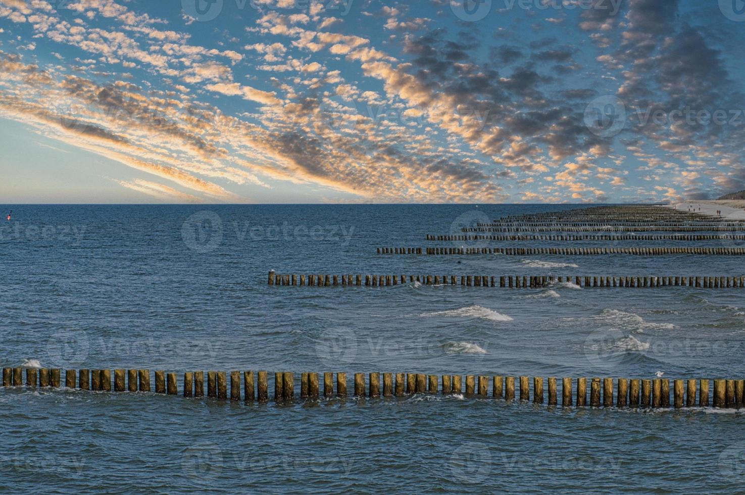 groynes on the beach of the Baltic Sea in Zingst. Waves break on the wood photo