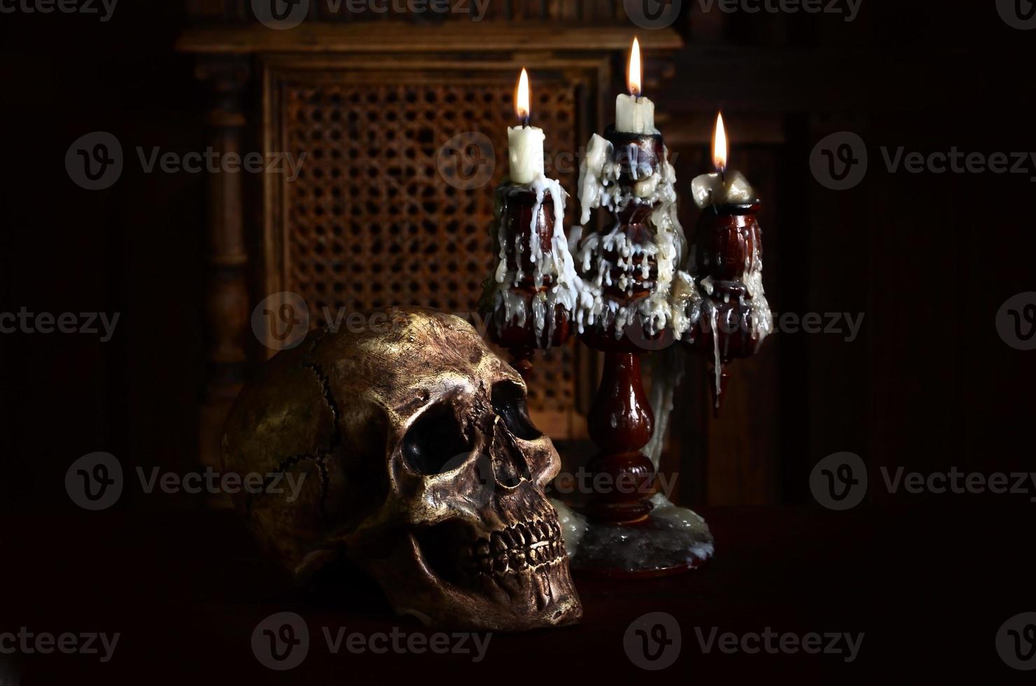 Old battered skull lies with an antique wooden candlestick photo