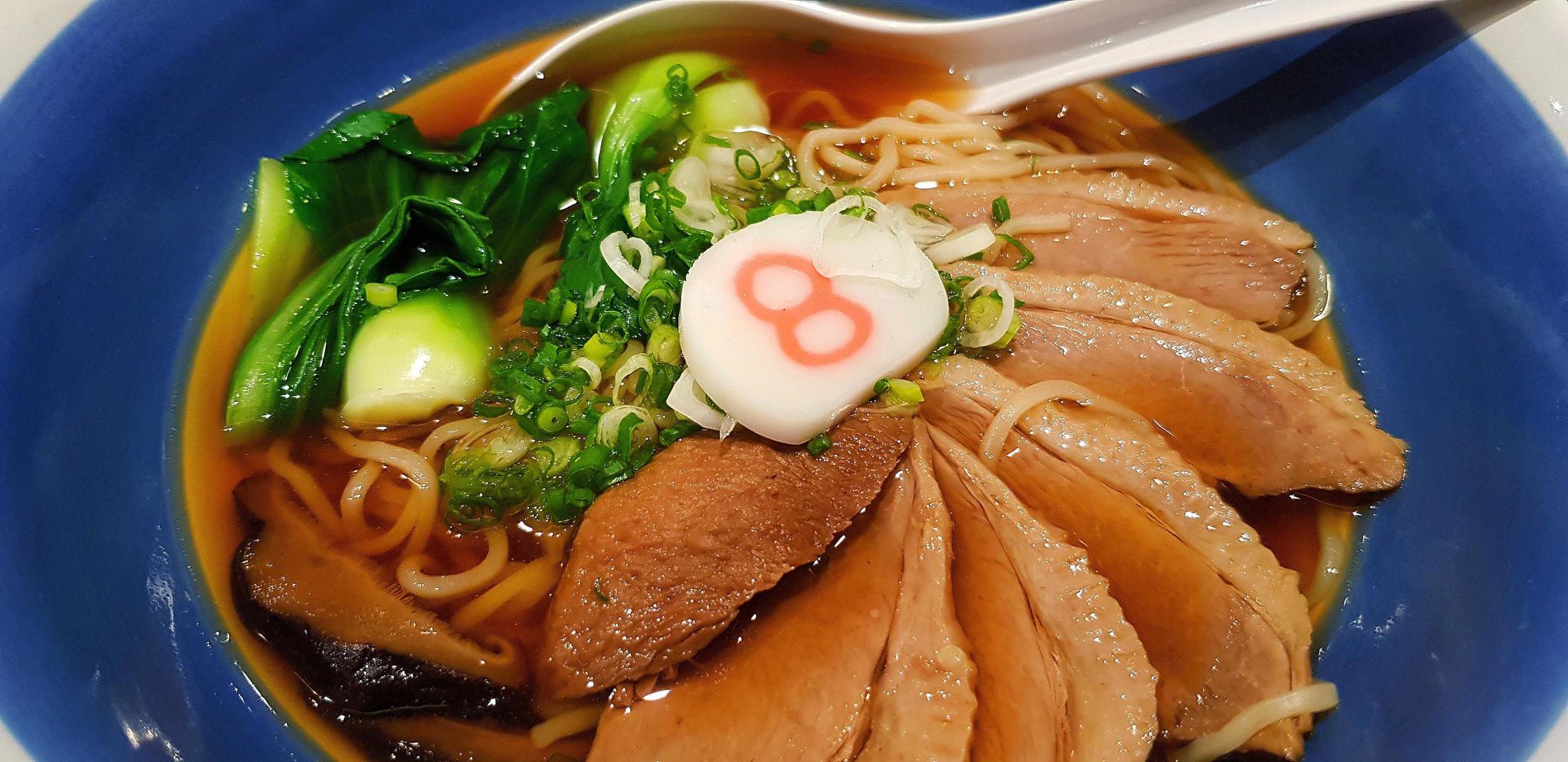 cierre los fideos ramen calientes con verduras, cebolla tierna en rodajas y pato guisado en sopa en un tazón azul. famosa comida japonesa en asia. foto