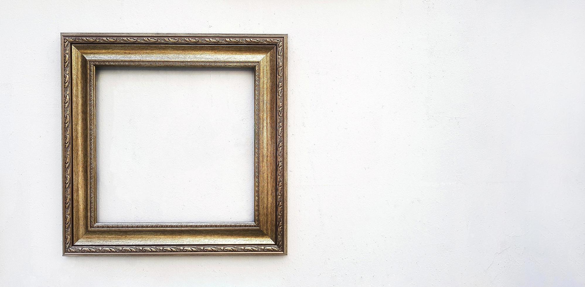 Golden or brown picture frame mockup on white concrete wall with copy space. Framework isolated on background. photo