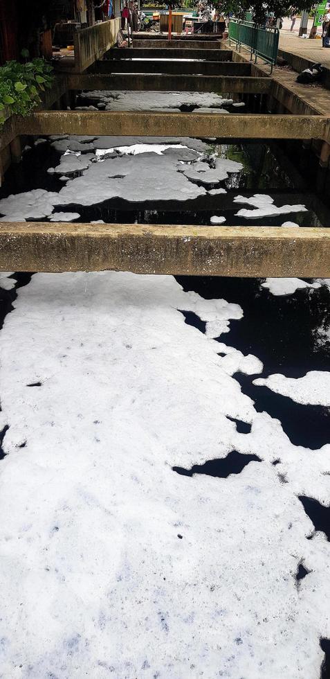 White pollution bubbles or detergent bubbles float in the community on the river. The filthiness and bad habits of human beings damage the environment or nature. photo