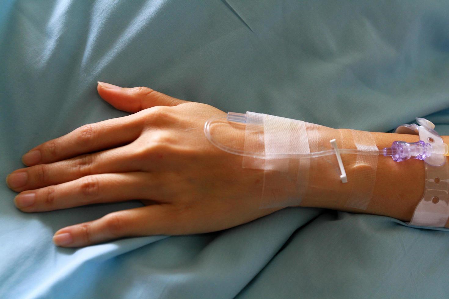 Close up patient's hands giving the saline solution on bed with copy space. Healthy, Medicine or Medical and injection. People cure sickness and fever at hospital or clinic. photo