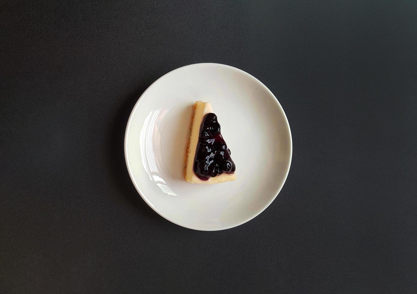 Top view of slice of blueberry cheesecake in white dish or plate with copy space. Flat lay of sweet snack or piece of dessert food. Berry cake with fruit cream. photo