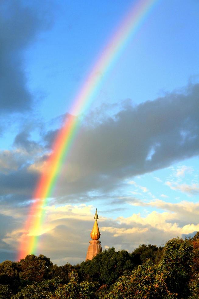 pagoda superior con bosque verde, arco iris y cielo azul con fondo de nubes. foto