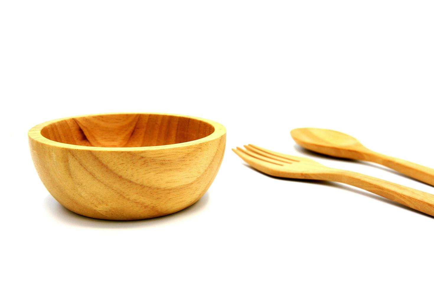 Wooden bowl and blurred wooden fork and spoon isolated on white background. Studio light concept photo