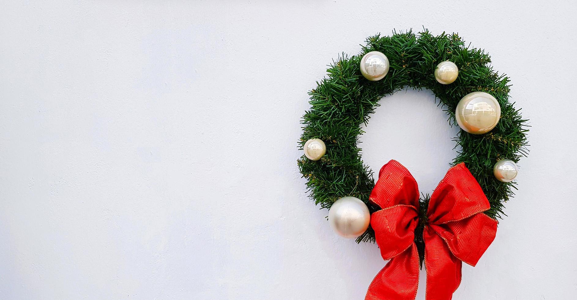 Christmas, happy new year wreath decoration with green leaves, ball and red ribbon isolated on white background with copy space. Object decorated for party, event or festival. photo