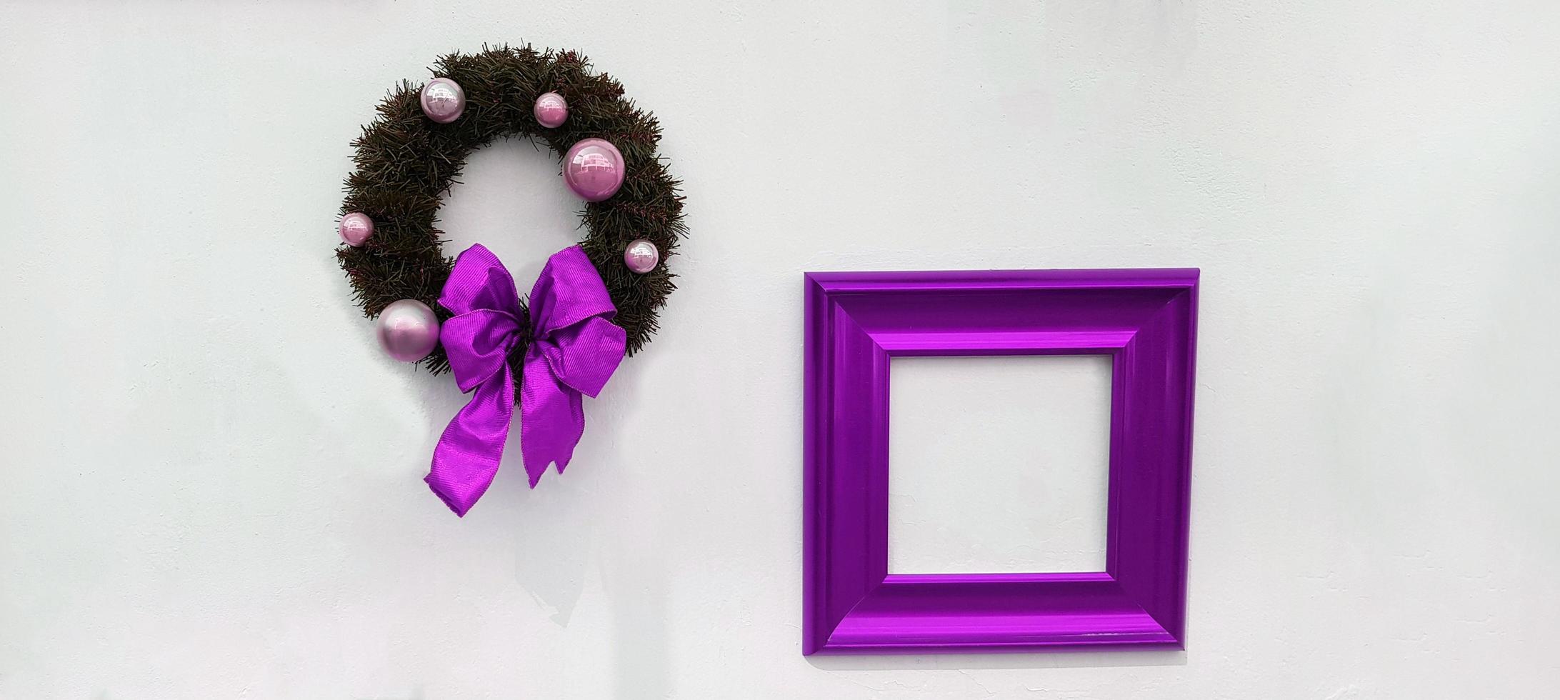 Christmas, happy new year wreath decoration with purple ribbon, white ball and violet picture frame for add wording isolated on white wall background. Object for party, festival with copy space. photo