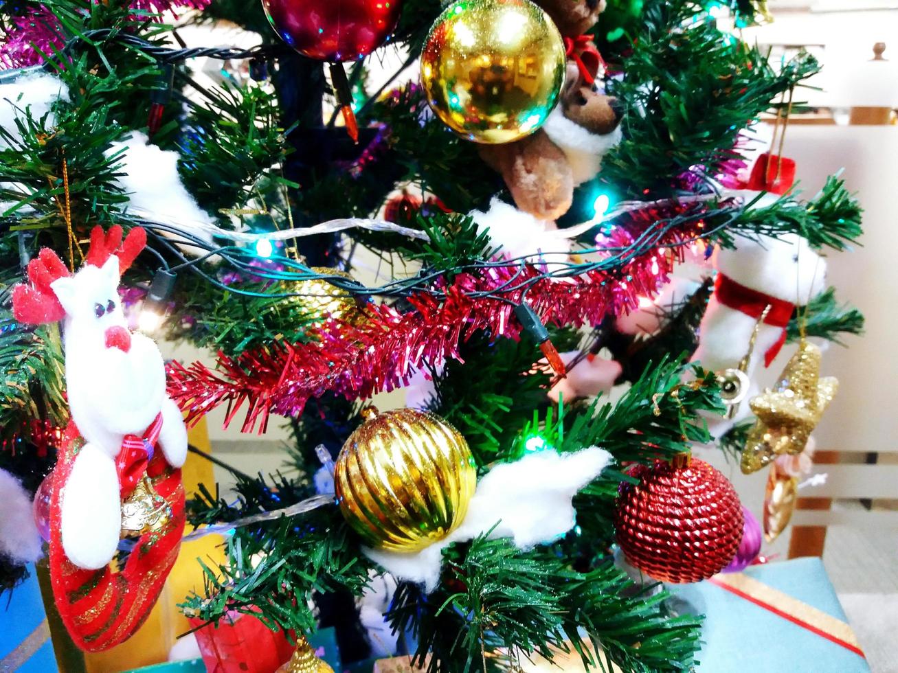 Colorful green christmas and Happy new year tree decoration with blue light, golden bell, red santa and ball soft focus photo