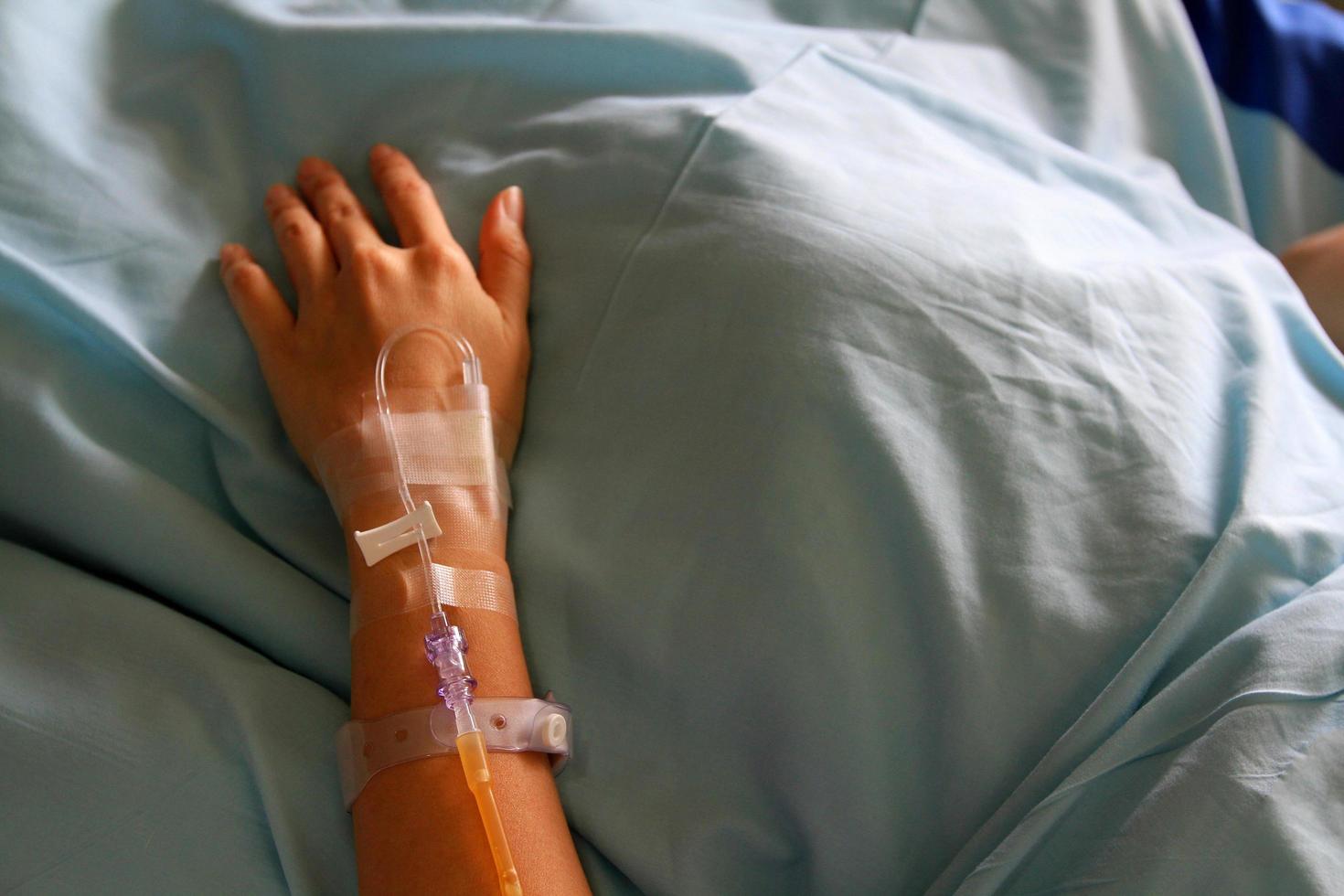 Patient's hands giving the saline solution on bed with copy space. Healthy, Medicine or Medical and injection. People cure sickness and fever at hospital or clinic concept. photo