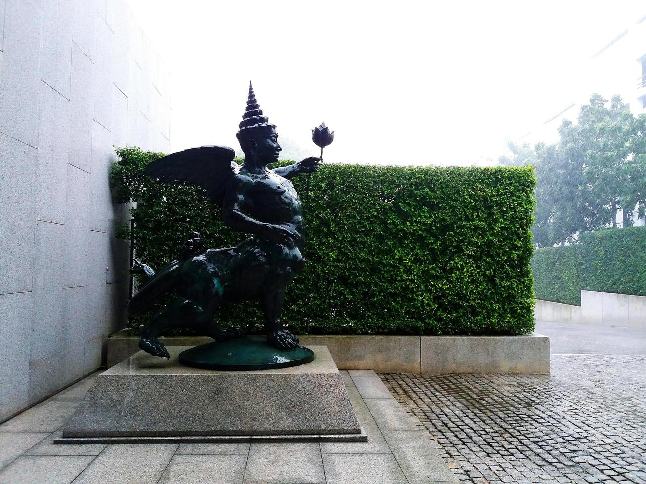Bangkok, Thailand - January 16, 2020  Imaginary animal statue with green tree background on raining day. Art object photo