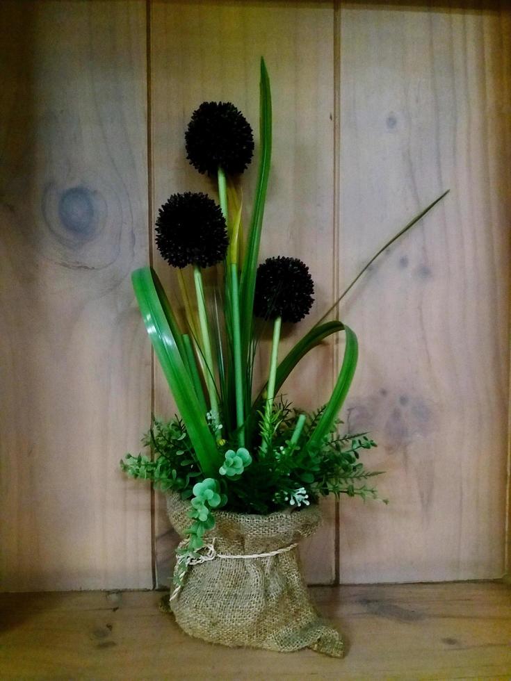 Flower with leaves in weave bag on shelf with wooden background. photo