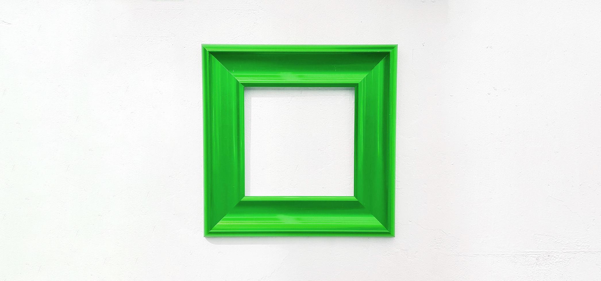 Green empty picture frame isolated on white wall with copy space. Object on concrete wallpaper for decoration for filling text or adding wording. photo