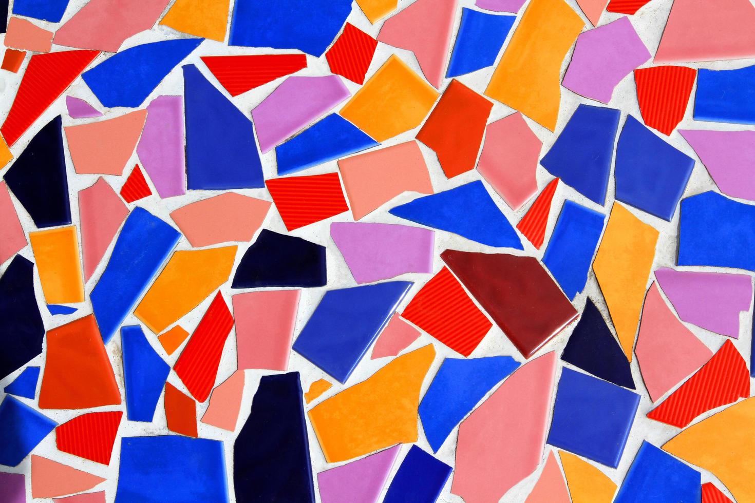 colorido de fondo de mosaico abstracto en la pared blanca. arte del papel pintado de azulejos rotos o agrietados de color rojo, naranja, azul, negro, rosa marrón y violeta o violeta. foto