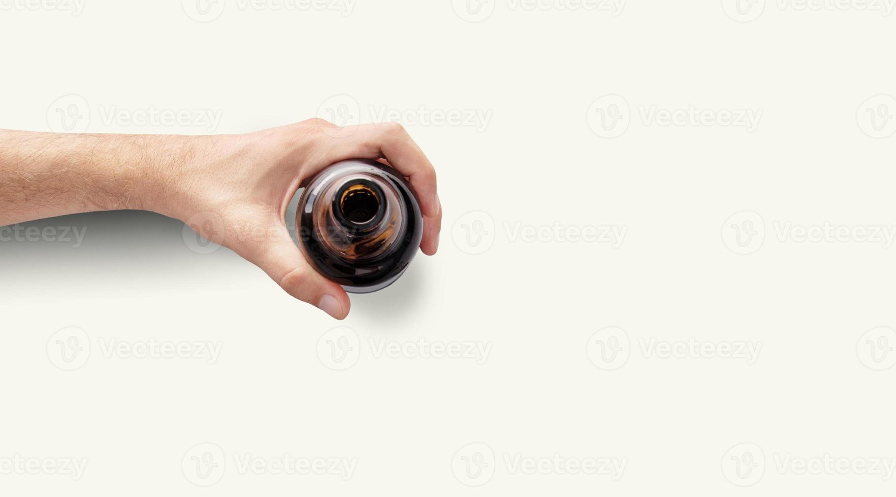 Man hand holding a bottle of beer top up view in a light white background with copy space photo