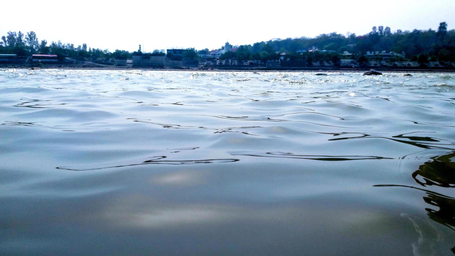 Water surface with ripples and sunrays reflections in ganga river at rishikesh photo