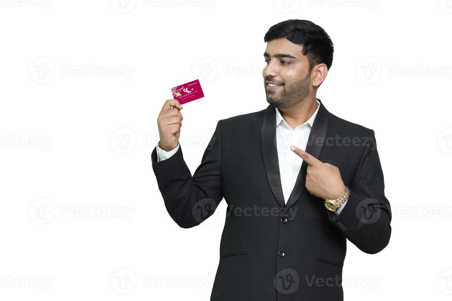 joven sonriente señalando con tarjeta de crédito. foto