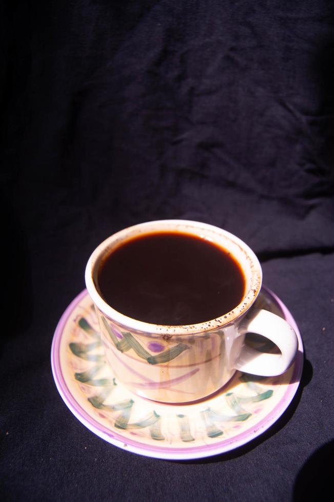 a glass containing brewed black coffee on a black background photo