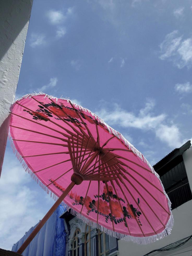 Pastel Pink umbrella with flower paint in local Thai style under blue sky white cloud sunny day photo