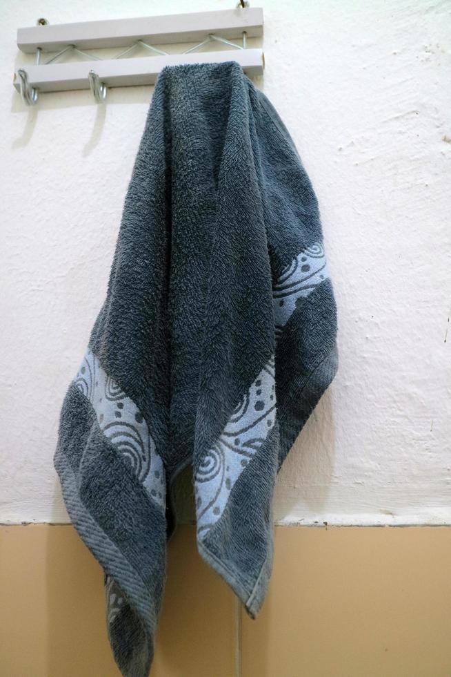 dark blue wet towel hung on the bathroom wall photo