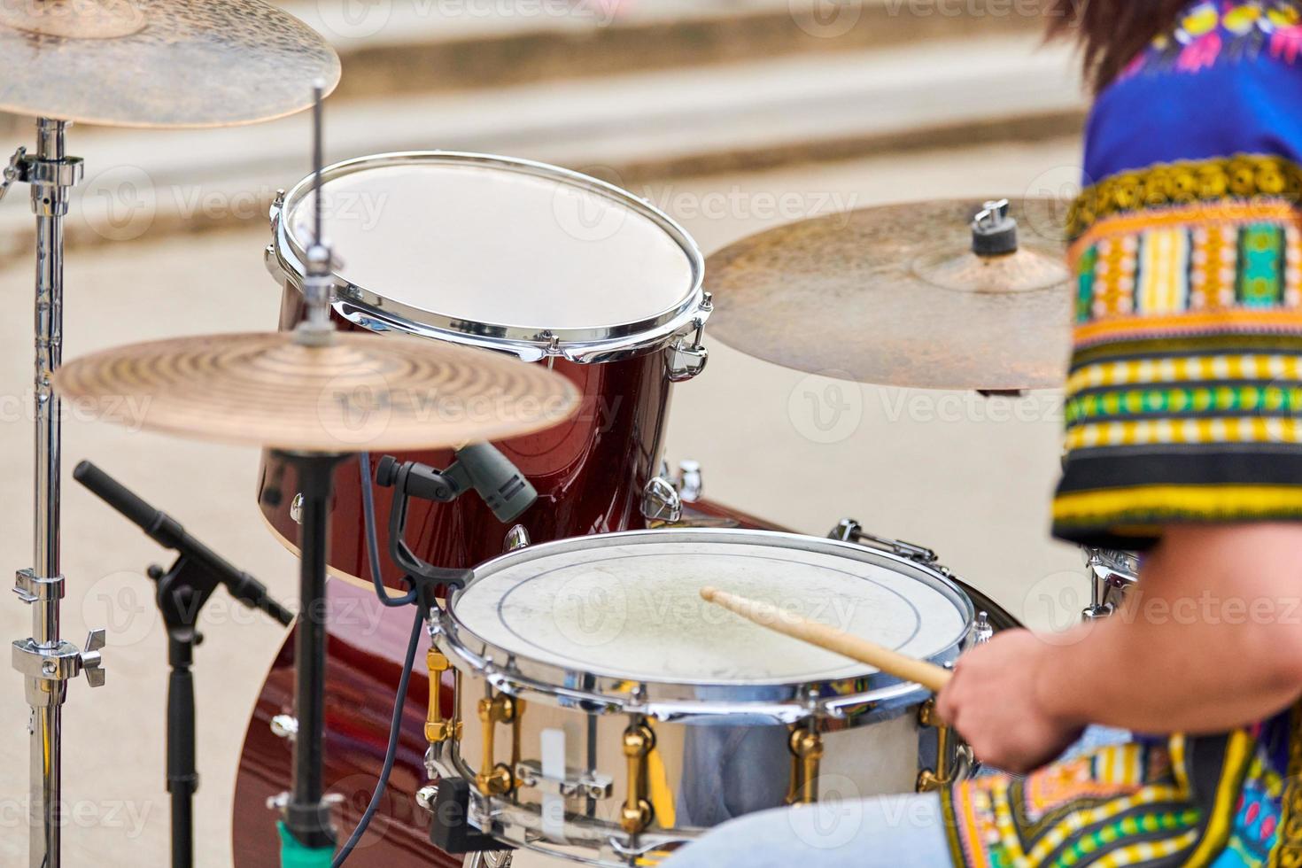 Drummer man playing drums percussion with sticks, drum kit on concert stage, drumsticks and drums photo