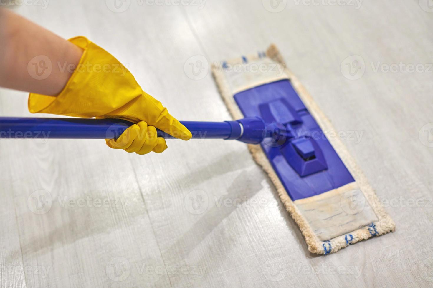 Girl in protective gloves cleaning floor using flat wet mop. photo