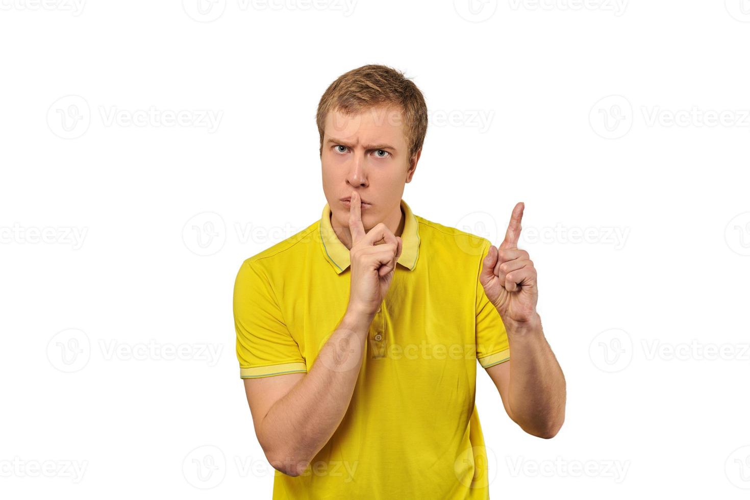 Funny male in yellow T-shirt asking to be quiet, silence gesture, white background photo