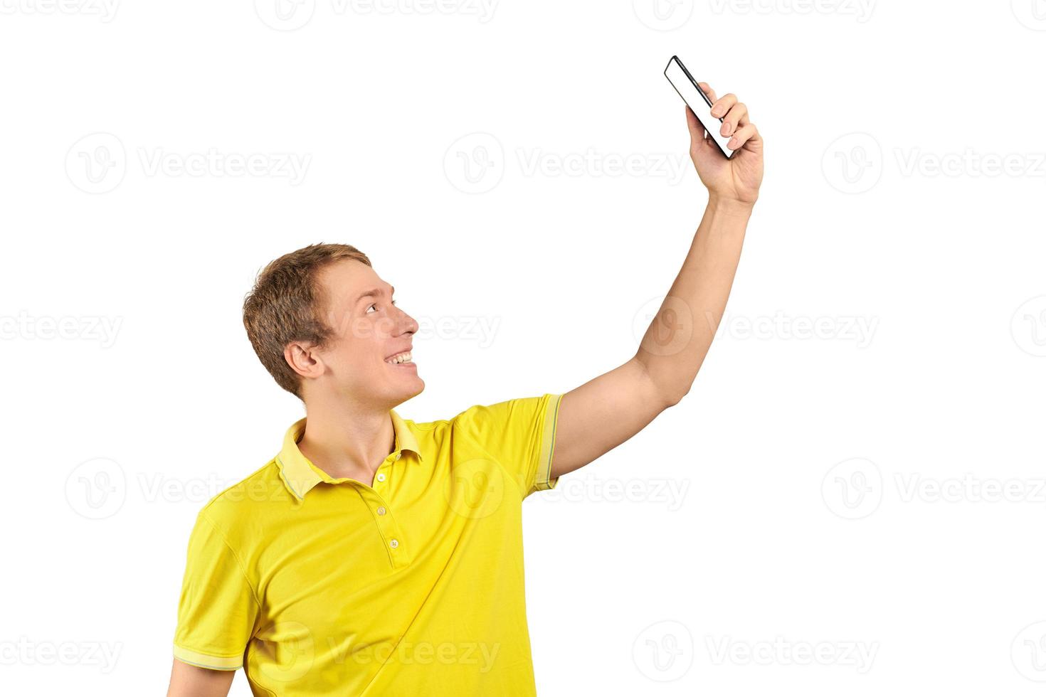 Funny guy in bright yellow T-shirt video chatting using video call with phone, smiling young man photo