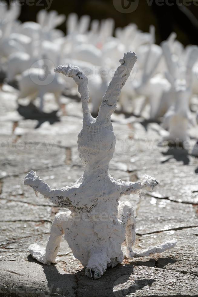 Big white rabbit statue made of plaster back view, outdoor art exhibition, artificial strange hare photo