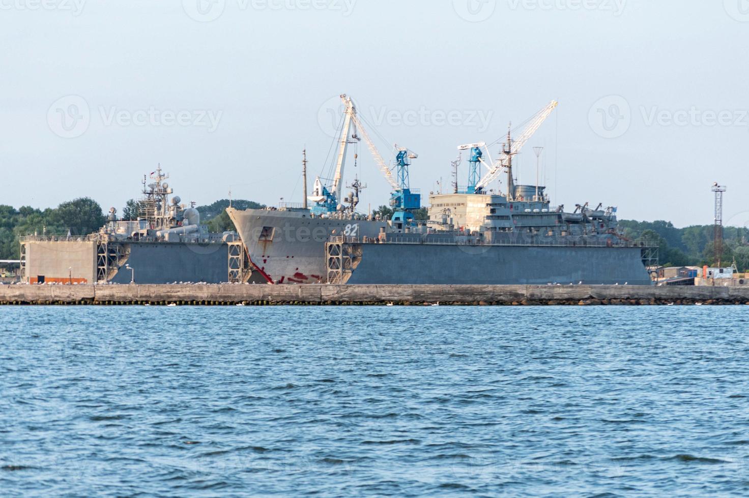 Large iron navy ships in shipyard for repair. Big crane in dockyard. Blue sea harbor photo