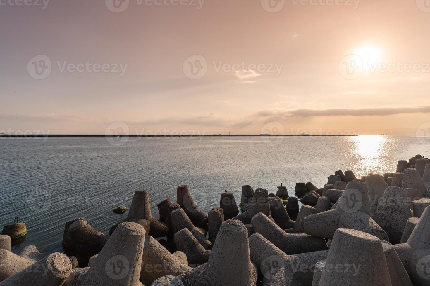 Tetrapod breakwaters in sea water. Beautiful sunset seascape with concrete tetrapodes for protect coastal structures from storm sea waves, effects of weather and longshore drift photo