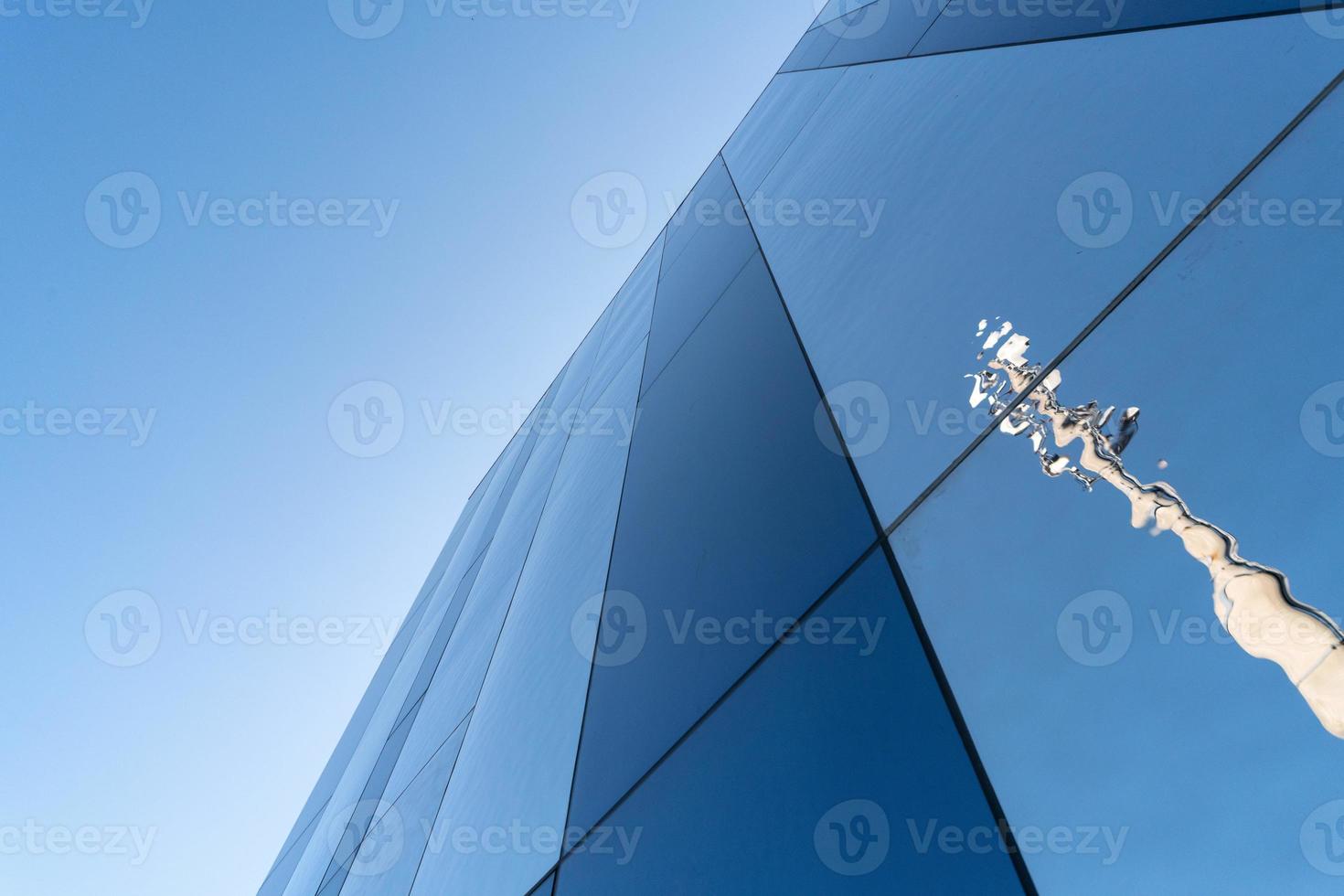 Mirror wall design of shopping center, copy space. Bottom view to modern texture of exterior decoration with reflection. Contemporary pattern of buildings. Looking up. photo