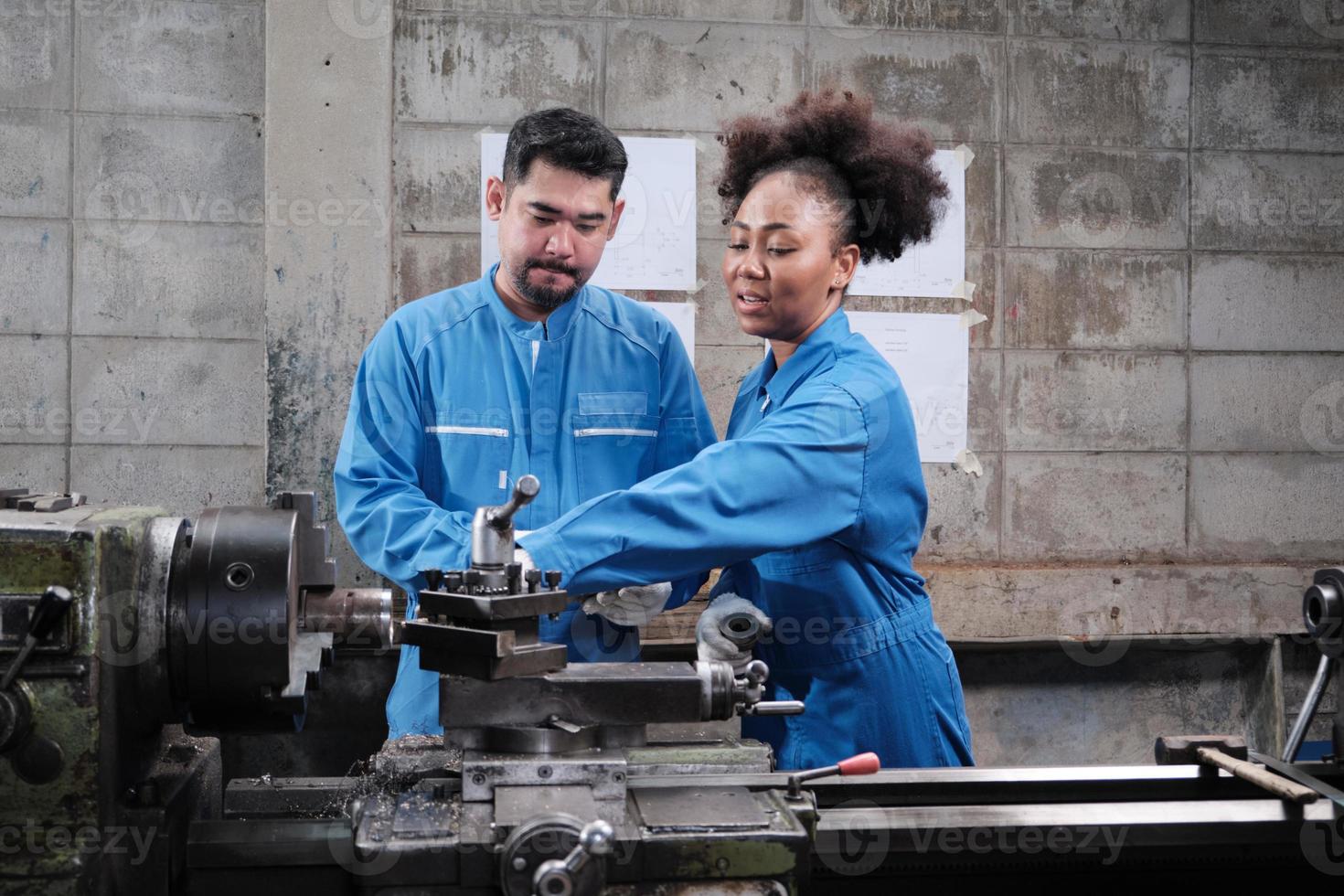 dos trabajadores profesionales de la industria con uniformes de seguridad y un socio de ingenieros trabajaron con herramientas de metalurgia de precisión y discutieron el dibujo mecánico para el taller de máquinas de torno en la fábrica de fabricación. foto