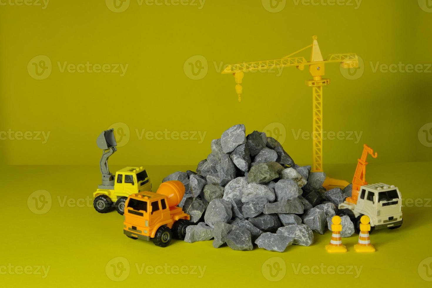 Models simulator on yellow background, construction vehicles toys, trucks, backhoes, and cranes site work, transport resource materials, rock, stone, and mortar, built real estate development business photo