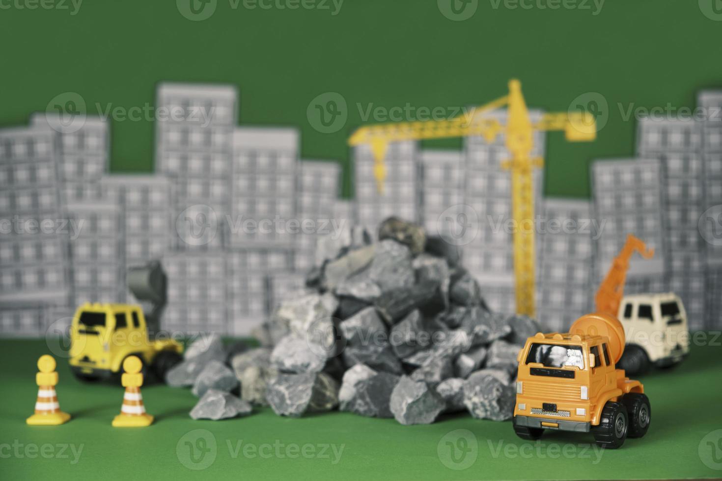 Models simulator on green background, construction vehicles toys, trucks, backhoes, and cranes work at site, transport resource materials, rock, and mortar, real estate business, and city development. photo