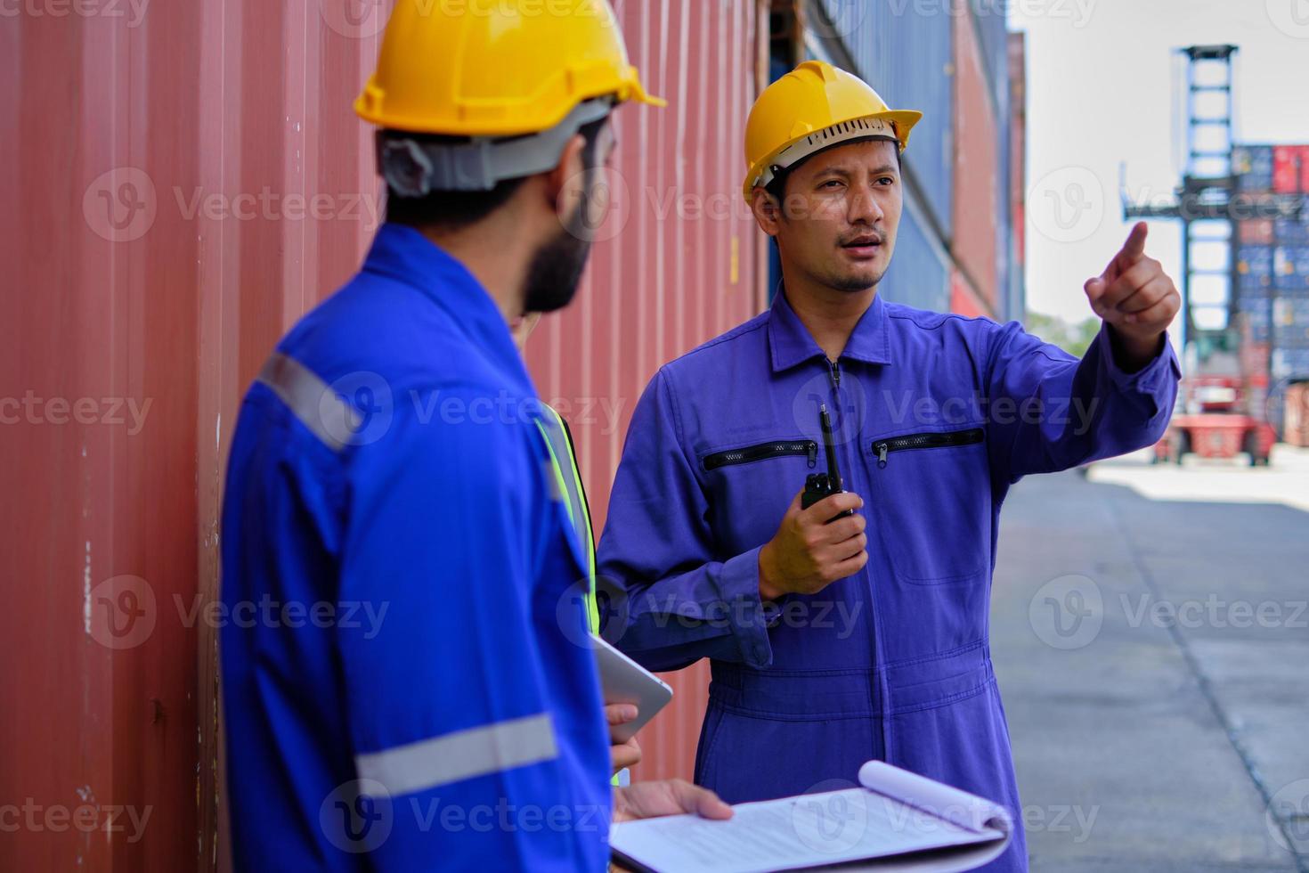 Group of three Asian workers, Thai people in safety uniforms and hard hats work at logistics terminal with many stacks of containers, loading control shipping goods for cargo transportation industry. photo