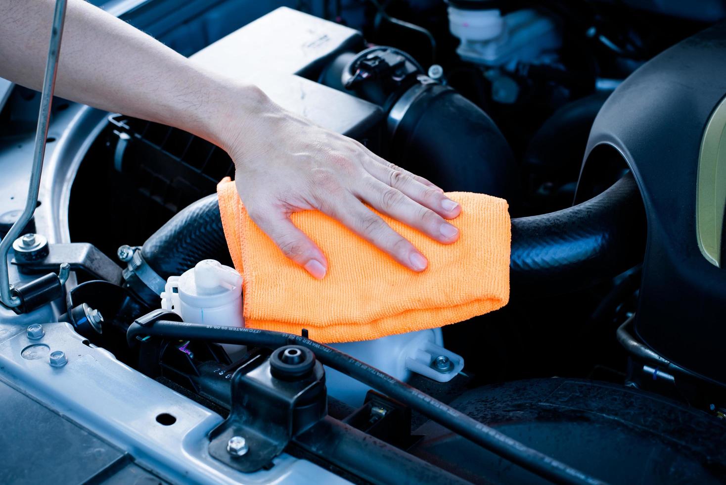 Wipe cleaning the car engine with orange microfiber cloth photo