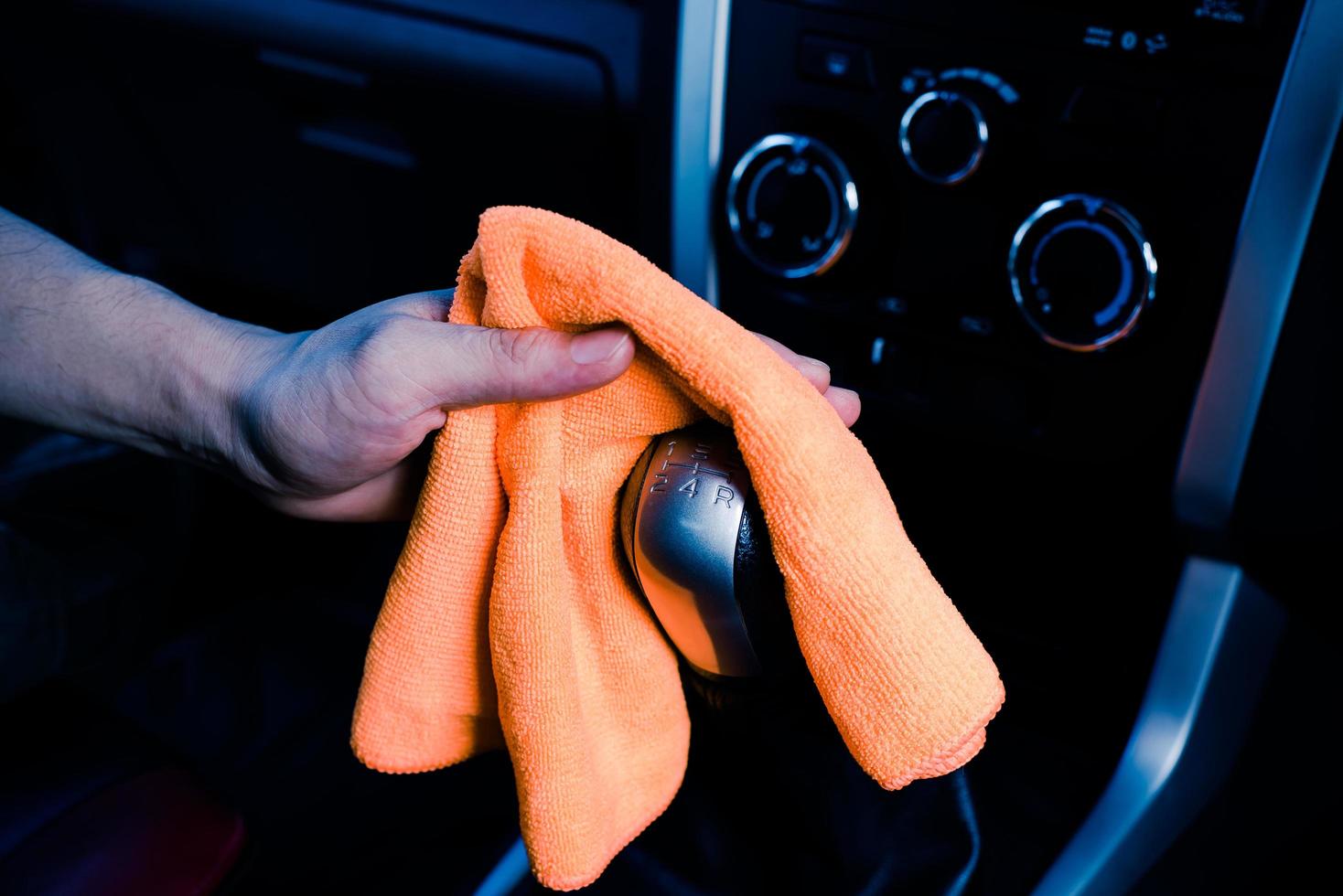 limpieza manual del interior del coche con un paño de microfibra naranja foto