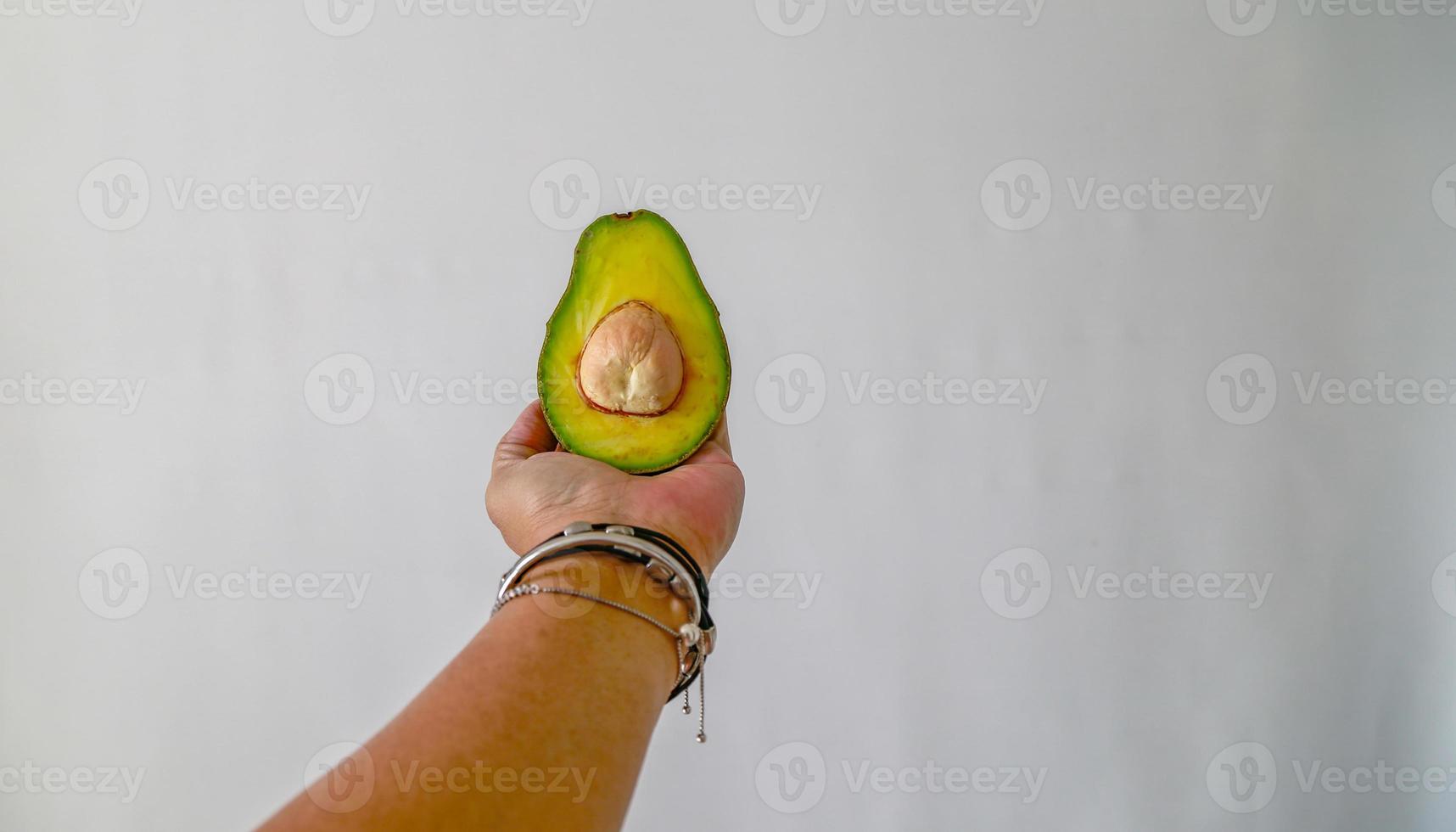 Half of avocado in left hand. photo