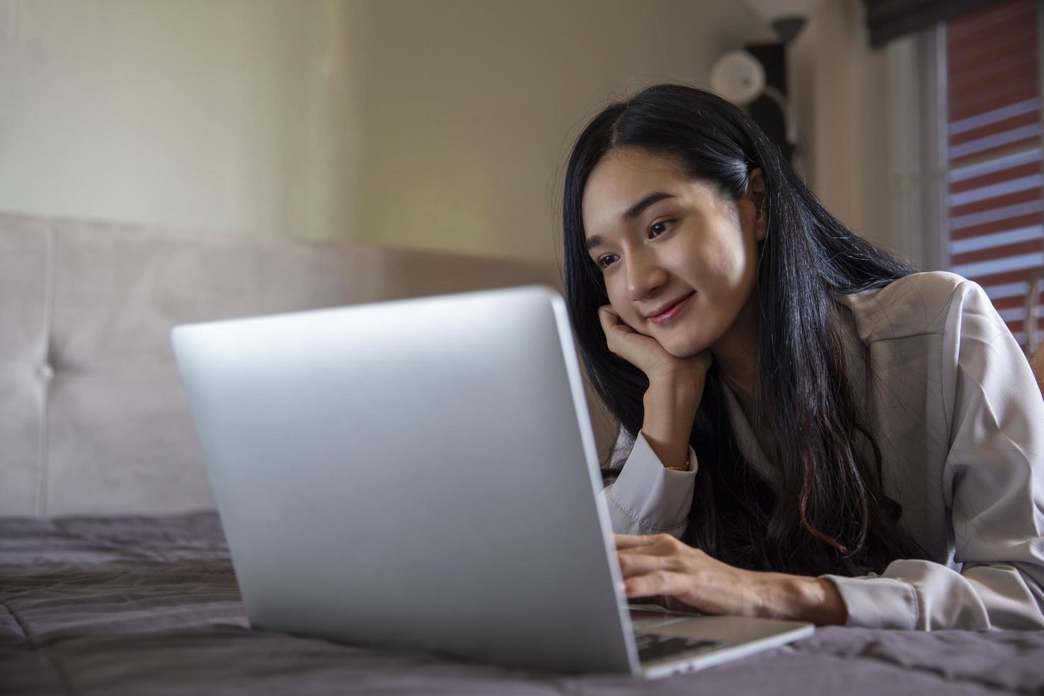 Beautiful Young Asian woman using laptop online chatting with colleagues on bedroom , having a video call on a laptop computer , work from home photo