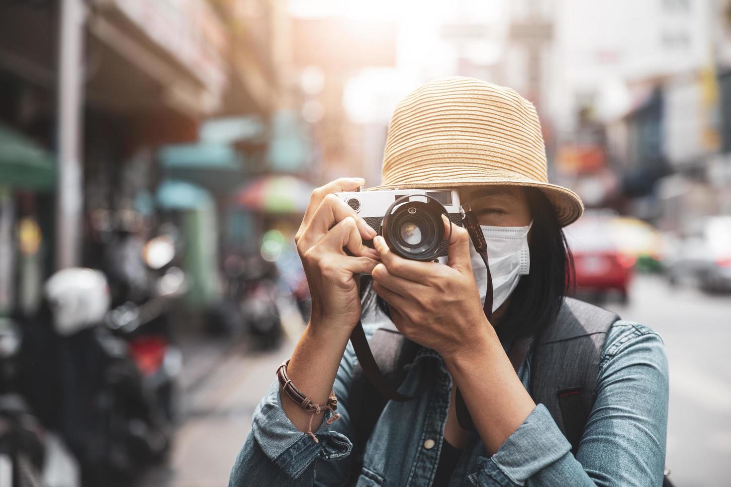 Asian women wearing surgical face mask traveler with camera travel of lifestyle portrait , outdoor summer concept photo