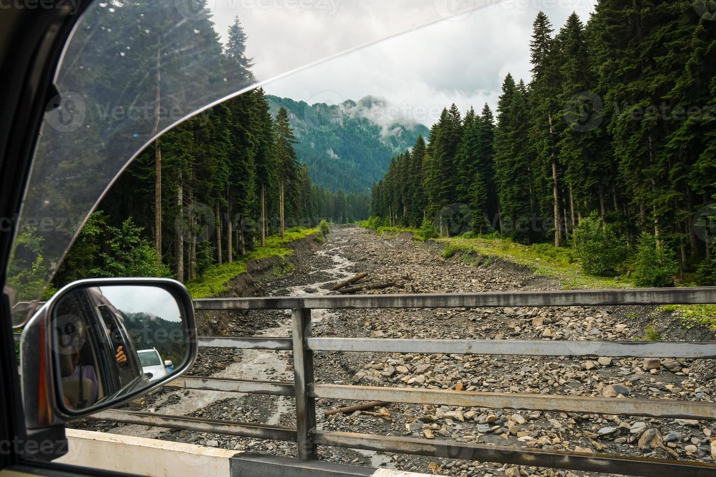 Front window view woods in nature on road trip traveling by rental car relax back seat take photo passenger. Lifestyle vacations vibes outdoor moody mountains view open window