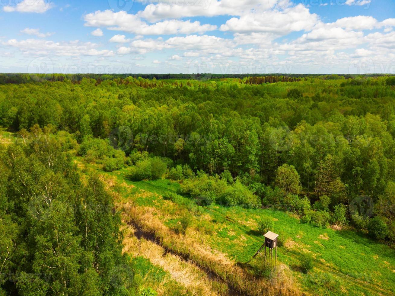 torre de caza de madera con amplia vista aérea en un día soleado. vista aérea desde arriba de grandes campos de tierra agrícola y una solitaria torre de caza de madera foto