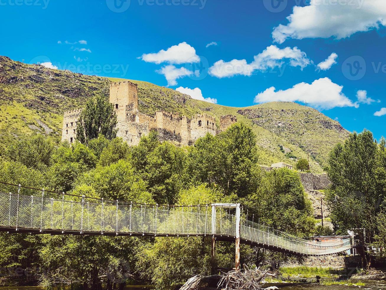 un puente colgante peatonal con vista desde lejos de la antigua fortaleza khertvisi foto