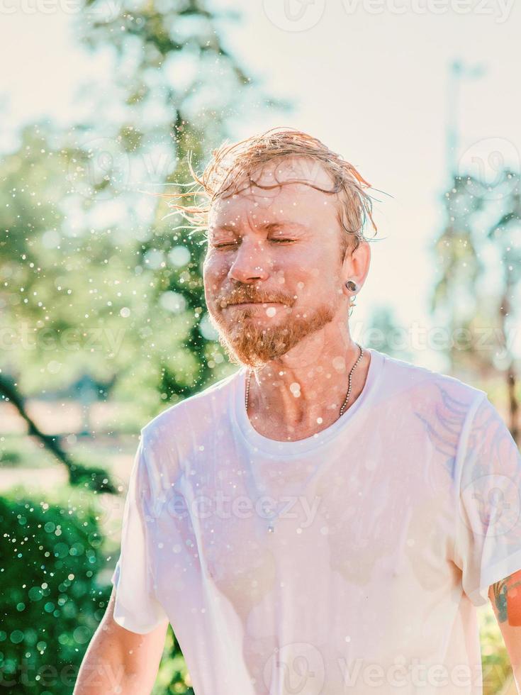 portrait of Caucasian man shaking head with water splashes. Summer fun, party, vacation, emotions, pleasure, relaxation, refreshment concept photo